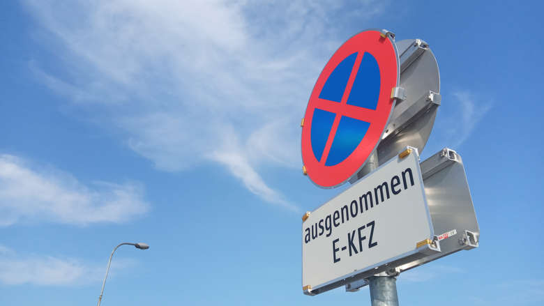 Verkehrsschild Halten und Parken verboten ausgenommen E-KFZ vor blauem Himmel