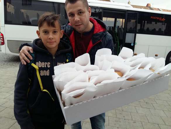 Mitarbeiter der Mobilitätszentrale verteilt ein Kipferl an einem Schüler