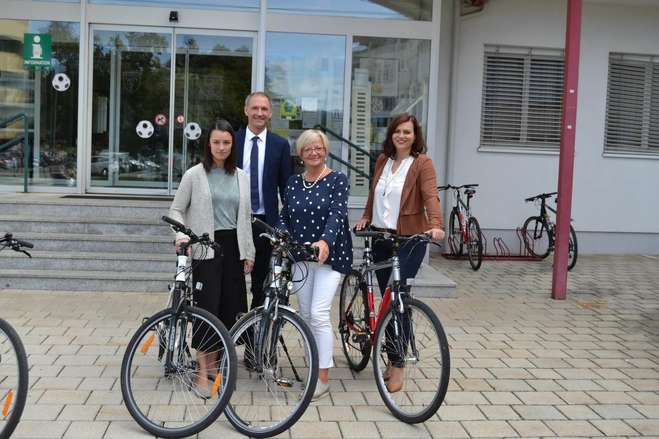 Landesrätin Astrin Eisenkopf mit Bürgermeisterin Salamon, Peter Zinggl und einen weiteren Person vor dem Rathaus mit einem Fahrrad